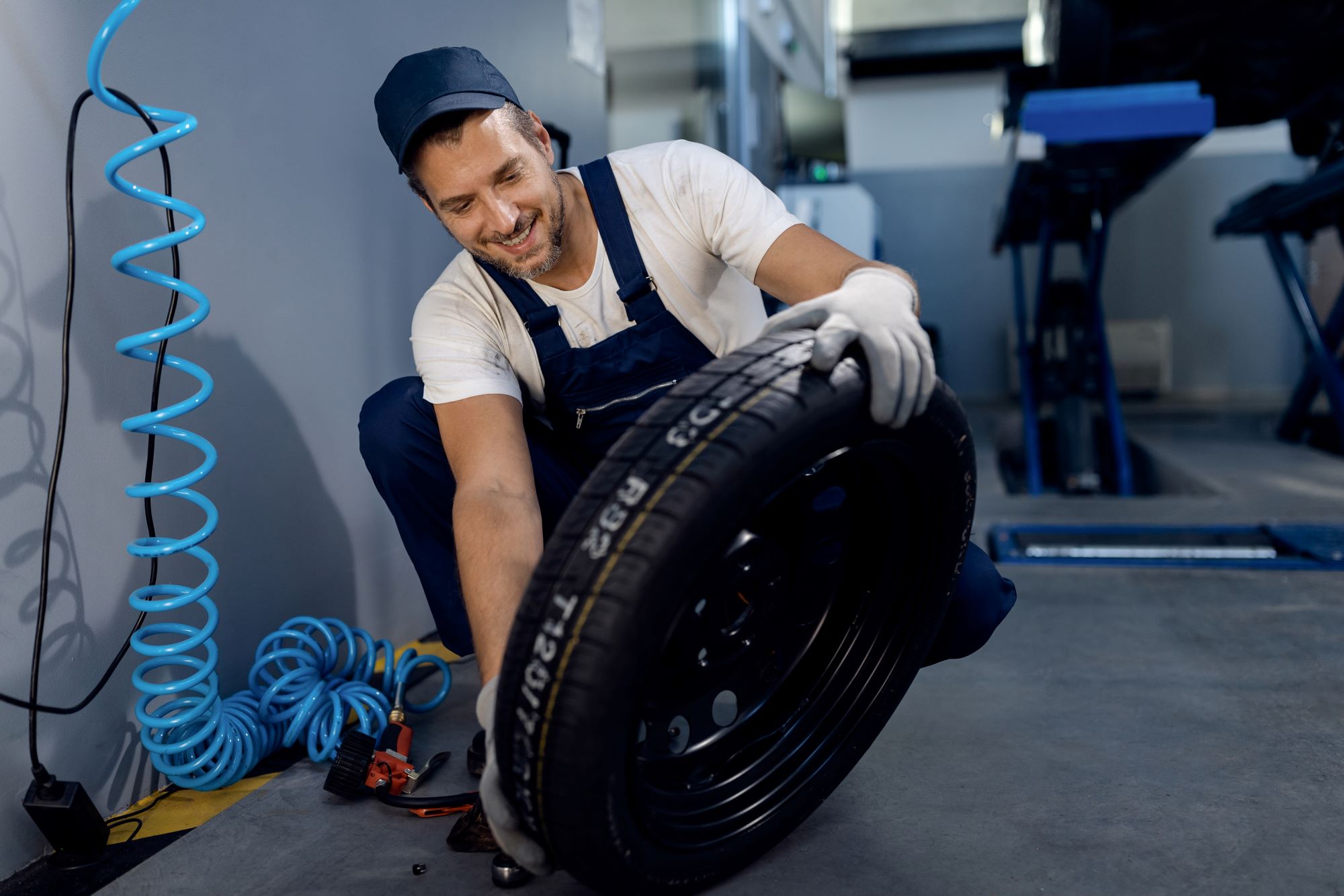 happy repairman checking car tire service workshop